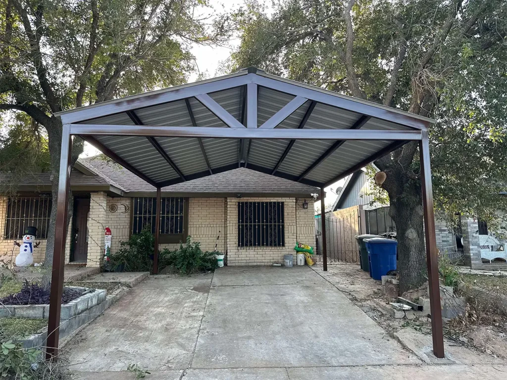Cobertizo para coche con techo metálico de 20 x 20 con techo a dos aguas y estructura de acero instalado en la entrada de una vivienda.