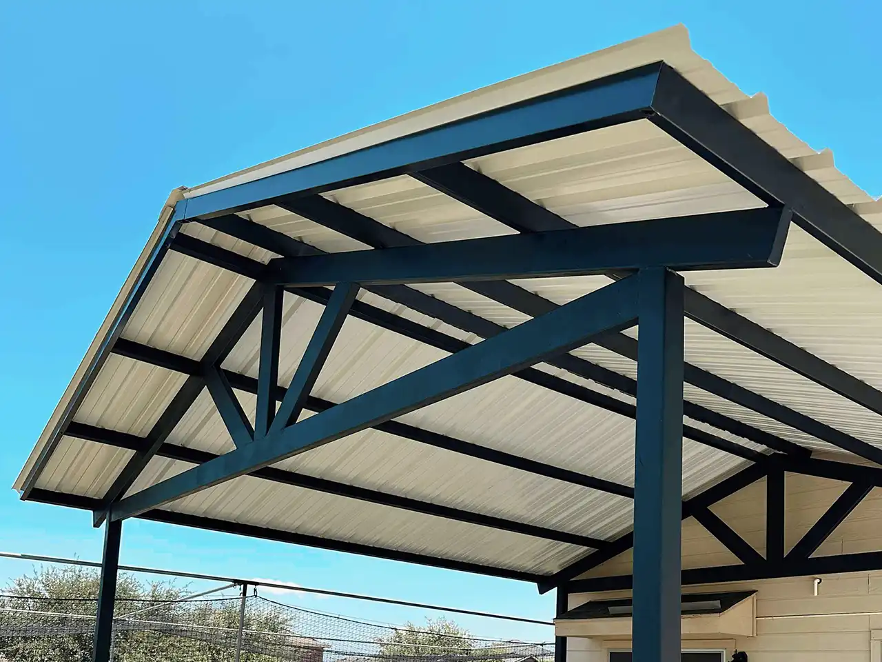Cochera con techo metálico de doble pendiente de 20 x 20 con láminas metálicas de colores y estructura de acero instalada en una vivienda.